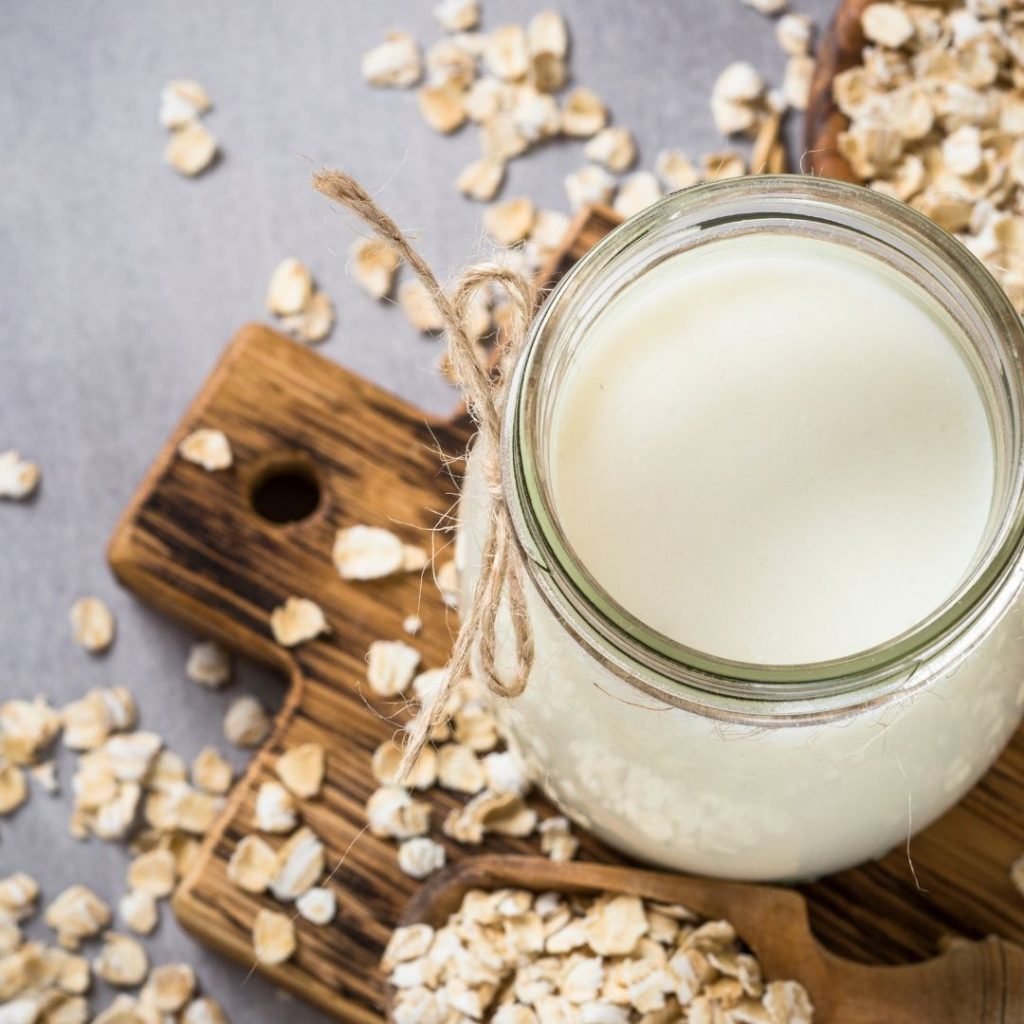 Oat milk in a glass jar, oats scattered around