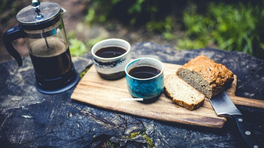 Coffee and sliced bread on a chopping board in the great outdoors