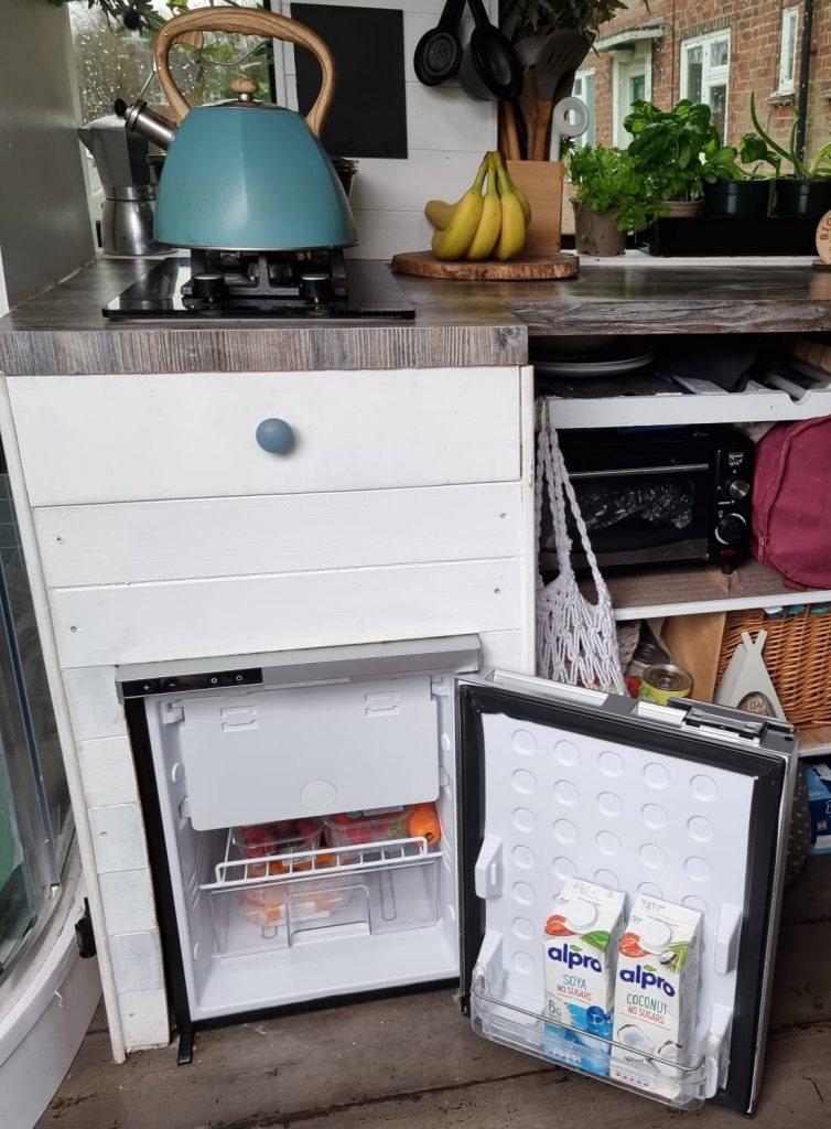 A 12v fridge with the door open in a campervan kitchen