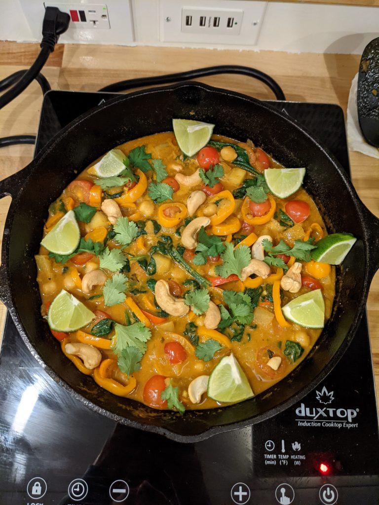 A meal garnished with lime wedges cooking on an induction hob