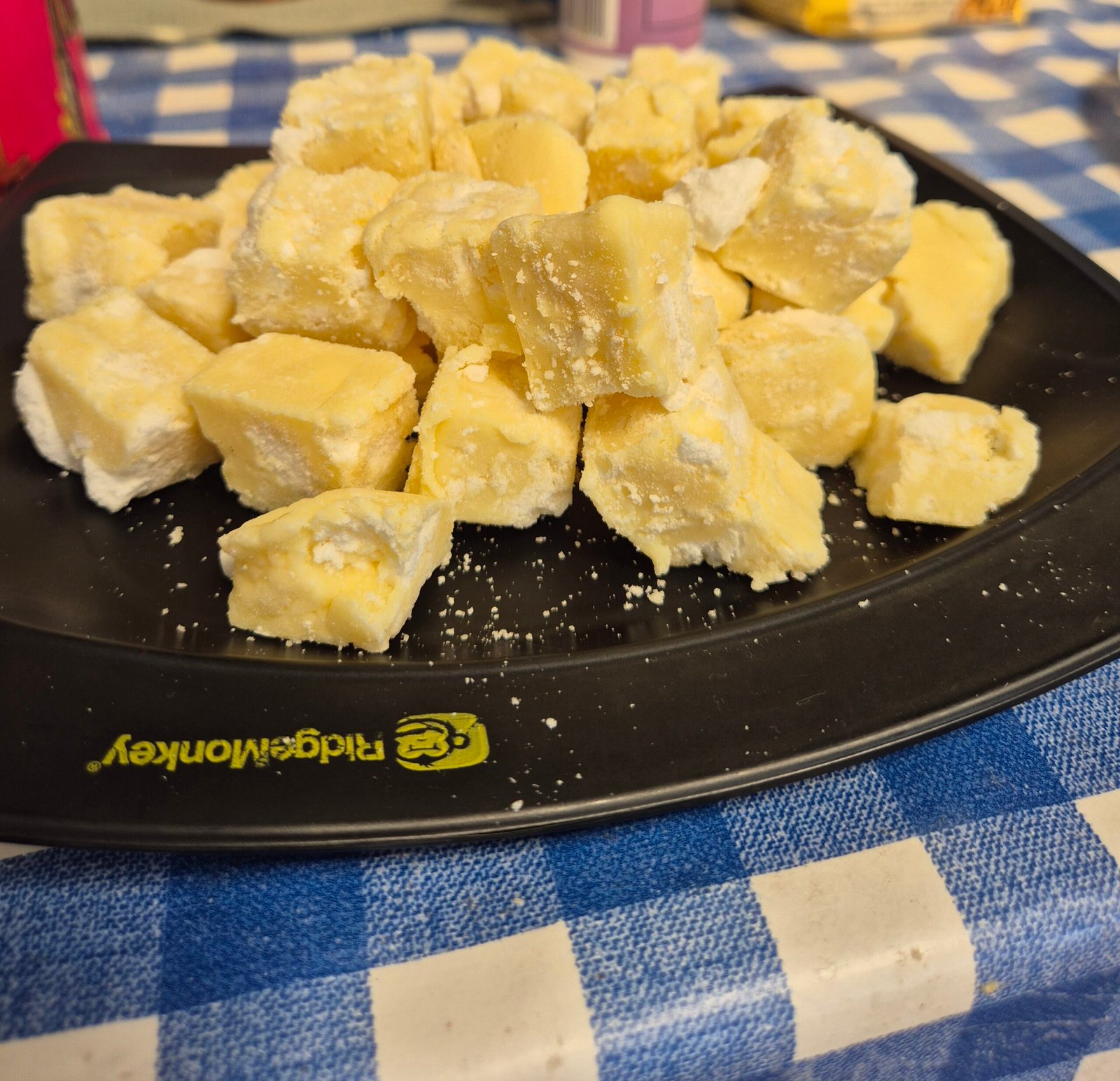 A black plate piled with fudge, on a blue and white tablecloth